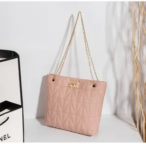 Detail of light pink quilted handbag featuring gold clasp lock and fine metal chain straps