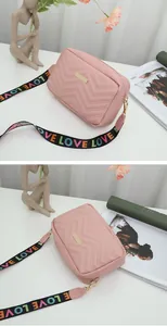 Detail of pink quilted camera bag featuring a wide embroidered LOVE strap and gold hardware