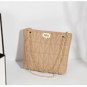 Close-up of geometric quilted camel shoulder bag with gold chain and metal lock detail