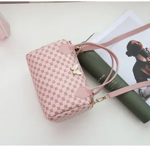 Close-up of light pink Boston bag with geometric pattern and white bow charm accessory