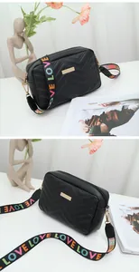 Detail of black V-quilted crossbody bag featuring a colorful LOVE letter fabric strap