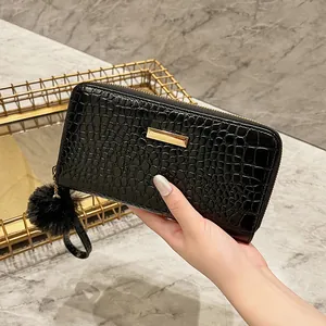 Women's black long crocodile embossed wallet with gold hardware and pompom keychain