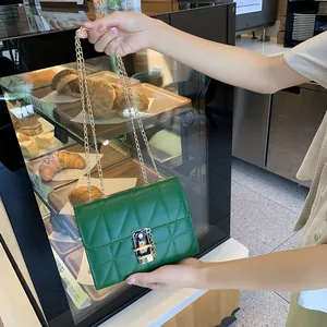 Quilted green crossbody bag with gold chain strap and flap lock shown in a bakery