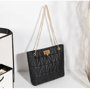 Detail of black quilted shoulder bag with gold chain strap and heart twist lock
