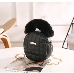 Détail du sac rond matelassé noir avec poignée en fourrure et chaîne dorée
