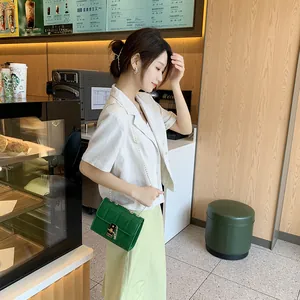 Green quilted chain shoulder bag with gold twist lock shown in a casual cafe setting