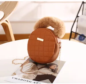Détail du sac rond matelassé caramel avec poignée en fourrure et plaque dorée