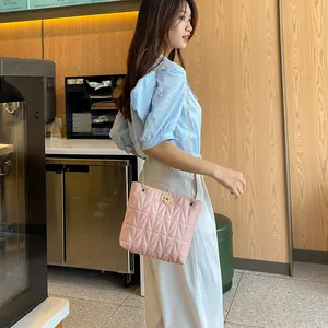 Pink quilted shoulder bag with gold chain strap worn by model in a cafe setting
