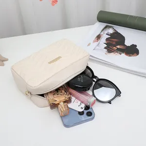 Chic cream quilted small crossbody bag filled with daily essentials on a white desk