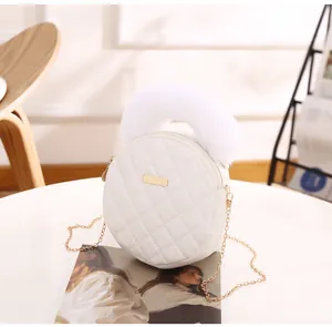 Vue détaillée du sac rond matelassé blanc avec poignée en peluche et plaque dorée