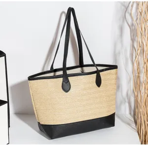 Détail d'un cabas en paille tissée avec bordure noire contrastée et fines bandoulières