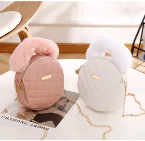Détail de sacs ronds matelassés rose et blanc avec poignées en peluche et chaînes d'or