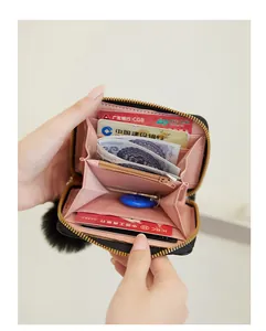 Detailed view of open woven zip wallet with pink lining and plush ball charm accessory