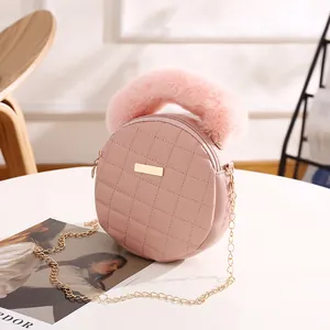 Sac à main rond matelassé rose avec poignée en fourrure et chaîne dorée sur table