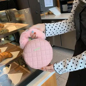 Petit sac rond matelassé rose avec poignée en fausse fourrure et décoration métallique