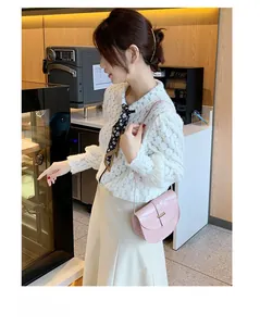 Detailed view of a light pink crocodile texture saddle bag with gold metal buckle