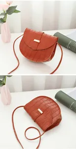 Macro detail of brick red crocodile embossed saddle bag with gold metal lock closure