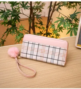 Detail of pink plaid long wallet for women with fuzzy pompom and leather wrist strap