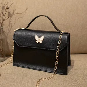 Elegante borsa in pelle nera con fibbia a farfalla bianca e catena dorata