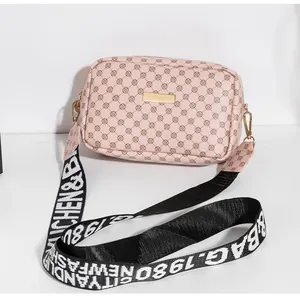 Détail du sac bandoulière rose avec imprimé floral et large sangle en nylon bicolore