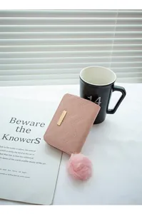 Vue détaillée d'un portefeuille matelassé rose pour femme avec pompon et détail doré