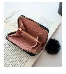 Detailed interior of woven texture coin purse with pink lining and plush ball charm