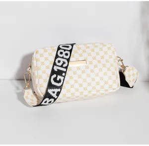 Détail d'un petit sac blanc à motifs floraux jaunes et large bandoulière logo