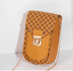 Detail view of mustard yellow crossbody bag with clover print and gold chain strap