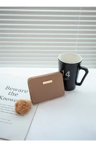 Détail du portefeuille matelassé marron avec barre dorée et breloque pompon en peluche