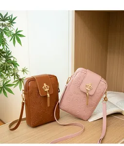 Detail of small crossbody phone bags with crown charms and embossed leather texture