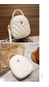 Detail of white quilted mini bag featuring golden floral clasp and adjustable strap