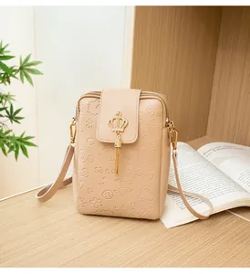 Detail of apricot mini crossbody bag featuring embossed crown and metal tassel charm