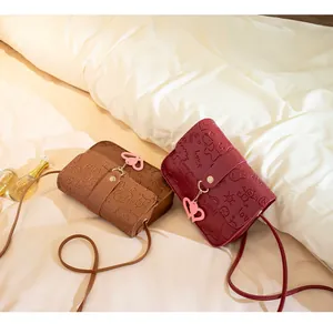 Detail of candy-colored leather crossbody bags with embossed cartoon patterns and heart charms