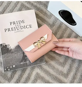 Détail du portefeuille rose en similicuir texturé avec boucle nœud papillon dorée