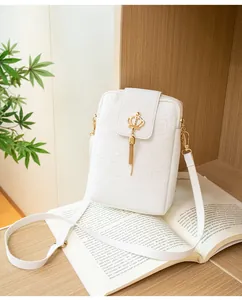 Detail of white embossed mini bag with gold crown buckle and delicate metallic tassel
