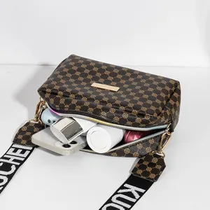 Sac bandoulière marron à motif avec large sangle lettrée et détails dorés montrant le rangement