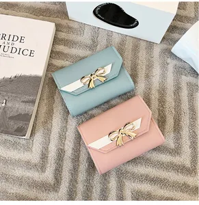 Détail de mini portefeuilles à trois volets en bleu et rose avec des nœuds en métal