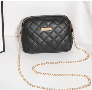 Détail du sac bandoulière noir matelassé avec chaîne dorée et plaque métallique