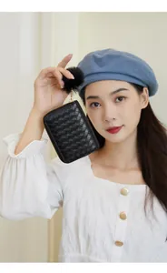 Detail of black woven leather coin purse with golden zipper and fluffy pompom charm
