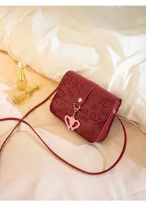 Detail of dark red embossed small crossbody bag with heart charm and cartoon pattern