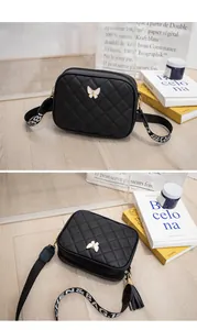 Détail du sac bandoulière matelassé noir avec ornement papillon et sangle lettrée