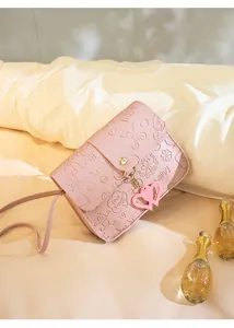 Macro detail of pink crossbody bag with heart charm and embossed cute patterns