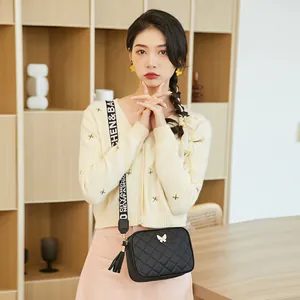 Sac bandoulière matelassé noir avec décor papillon doré et large sangle de style
