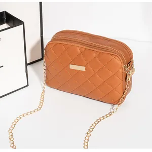 Détail de la pochette matelassée camel avec triple fermeture éclair et chaîne dorée