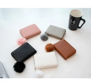 Group view of five woven texture coin purses in various colors with plush ball charms