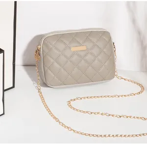 Détail du sac bandoulière gris matelassé avec double zip et chaîne dorée
