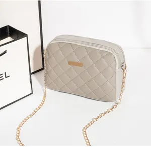 Détail du sac bandoulière gris matelassé avec double fermeture éclair et plaque dorée