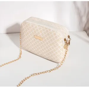 Détail de la double fermeture éclair et de la chaîne dorée sur le sac bandoulière beige matelassé