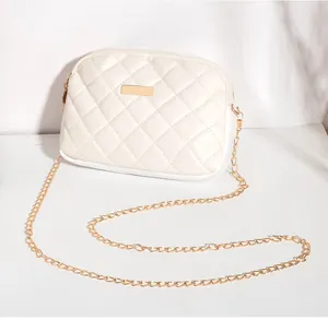 Détail du motif matelassé et de la plaque métallique dorée sur le petit sac blanc