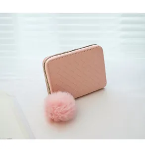 Close-up of light pink woven leather wallet featuring a soft fluffy pompom keychain